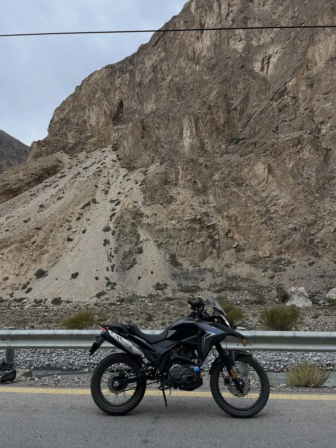 Adventure motorcycle beside a rocky mountain road in northern Pakistan